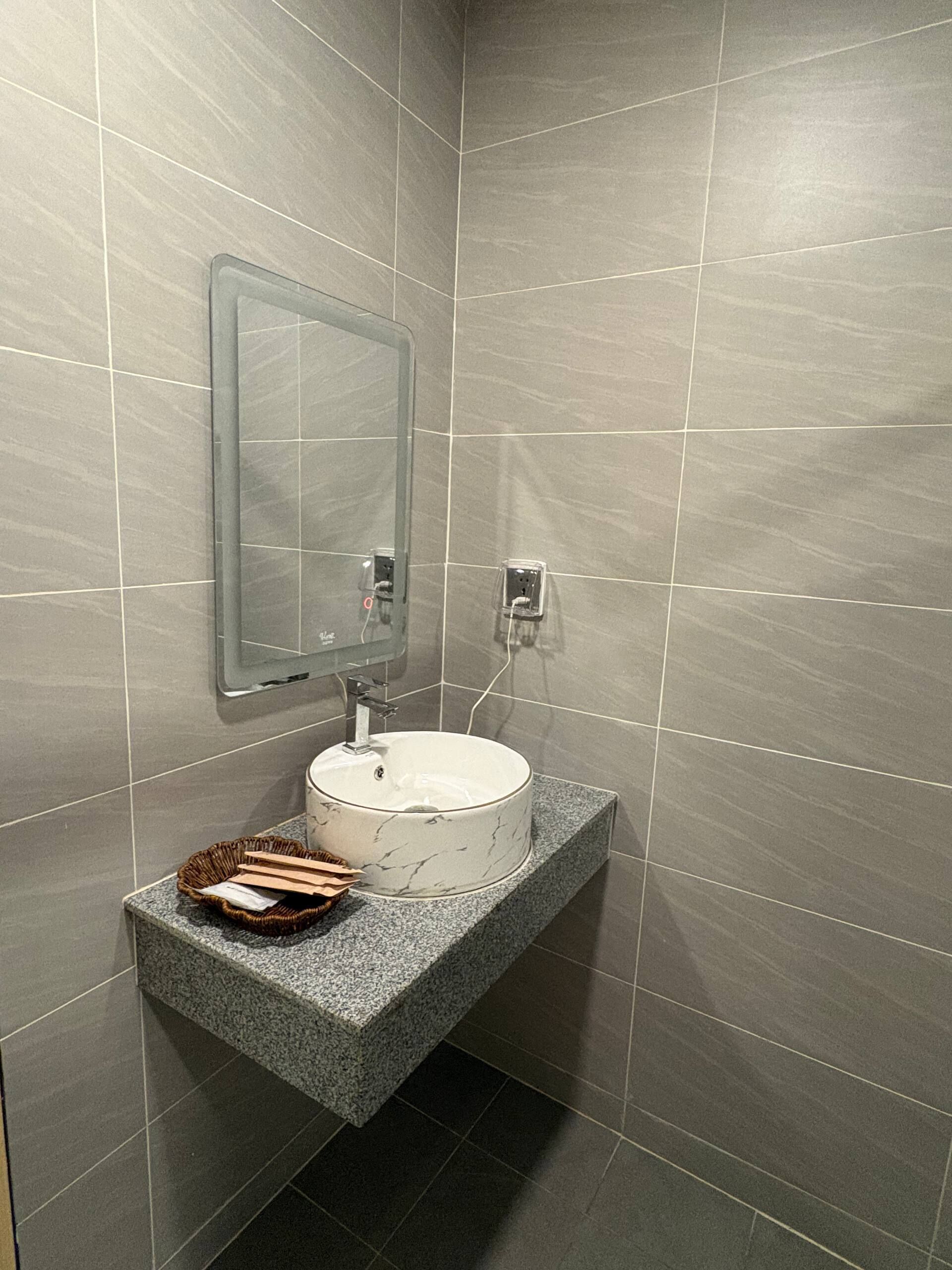Une salle de bain avec un lavabo en marbre blanc, un miroir et un comptoir en granit.