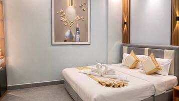 A modern hotel room with a large bed, a ceiling light fixture, and a framed artwork on the wall.