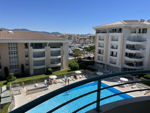 A residential building with balconies, a swimming pool, and a marina in the background. - OPEN Residence, 1-bedroom apartment (41m²), sleeps 5, close to port, beaches, swimming pool, private parking (Fréjus)