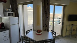 Una pequeña cocina con refrigerador, microondas y una mesa de comedor con sillas.