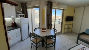 Un espacio habitable compacto con kitchenette, comedor y un balcón con vistas.