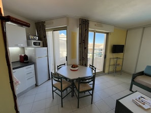 A compact living space with a kitchenette, dining area, and a balcony with a view. - OPEN Residence, 1-bedroom apartment (41m²), sleeps 5, close to port, beaches, swimming pool, private parking (Fréjus)