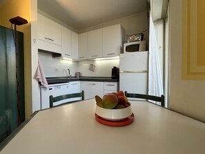 A kitchen with white cabinets, a microwave, and a bowl of fruit on the table. - OPEN Residence, 1-bedroom apartment (41m²), sleeps 5, close to port, beaches, swimming pool, private parking (Fréjus)