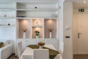 A modern hotel room with a dining area, a white sofa, a table with a fruit bowl, and a potted plant. - Olimpia, a luxury apartment in the heart of Monteverde in Rome (Roma)