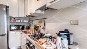 Moderni keittiö, jossa on ruostumattomasta teräksestä valmistetut kodinkoneet, puinen työtaso ja monipuolinen valikoima elintarvikkeita.