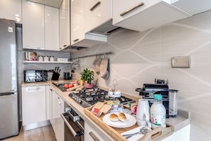 A modern kitchen with stainless steel appliances, a wooden countertop, and a variety of food items. - Olimpia, a luxury apartment in the heart of Monteverde in Rome (Roma)