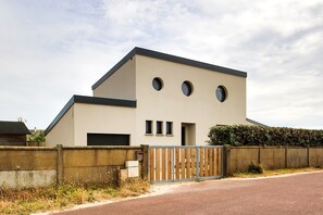 Um edifício moderno com teto plano, entrada com portão e muro de concreto.