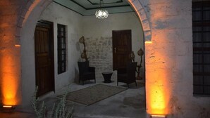 An arched doorway leading to a room with a stone wall, wooden door, and a hanging light fixture. - Hasbahan Konak (Sanliurfa)