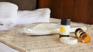 A bed with a patterned bedspread, a bottle of conditioner, and a rolled-up towel. - Hasbahan Konak (Sanliurfa)