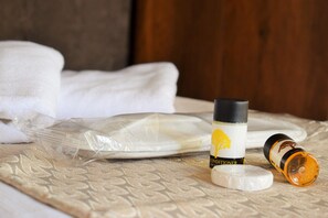 A bed with a patterned bedspread, a bottle of conditioner, and a rolled-up towel. - Hasbahan Konak (Sanliurfa)