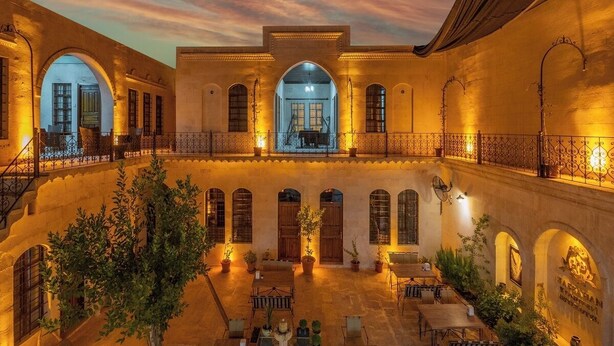A courtyard with a central open space, arches, and potted plants. - Hasbahan Konak (Sanliurfa)
