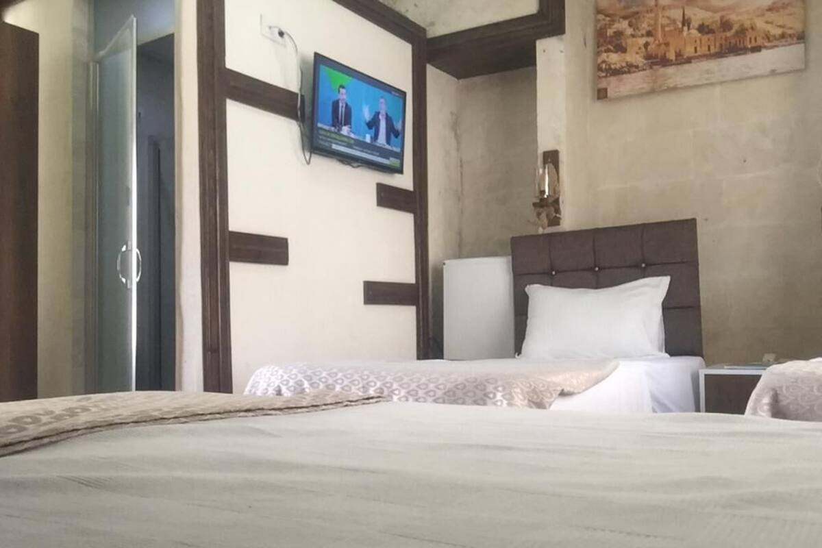 A hotel room with a bed, a television mounted on the wall, and a painting above the bed.