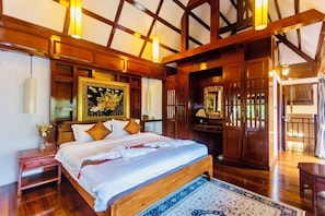 Een slaapkamer met een groot bed, houten balken in het plafond, een schilderij en een nachtkastje.