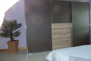 Ein Schlafzimmer mit einem Bett, einem Schiebetürenschrank und einer Topfpflanze.