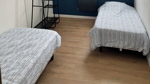 Ett rum med två sängar, ett element, ett fönster med utsikt och en stege.