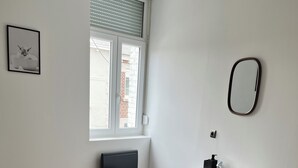 Ett modernt badrum med en vit tvättställ, en spegel och ett fönster med persienner.