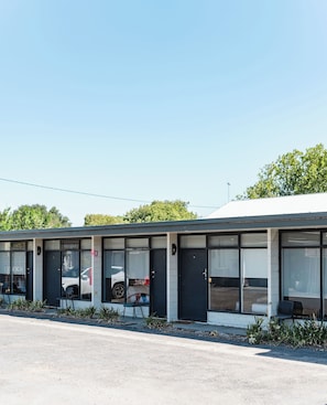 Un bâtiment moderne doté de grandes fenêtres, d’un toit plat et d’un parking situé à l’avant.