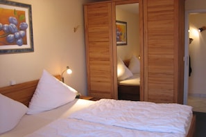 Ein Schlafzimmer mit einem Bett, weißen Kissen, einem Holzschrank und einem Gemälde an der Wand.