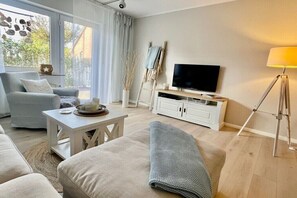 A modern living room with a sofa, a coffee table, a TV, and a lamp. - Holiday home with 3 bedrooms (Wangerland\/Horumersiel\/Schillig)