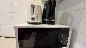Een magnetron met een broodrooster en een koffiezetapparaat erboven.