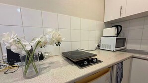 Een keuken met een magnetron, een fornuis en een vaas met bloemen op het aanrecht.