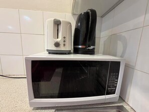 Ein Mikrowellenofen mit einem Toaster und einer Kaffeemaschine darauf.