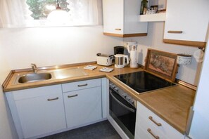 Eine kleine Küche mit Spüle, Toaster, Kaffeemaschine und Backofen.