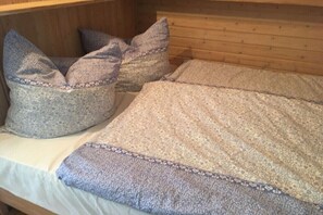 Ein holzgetäfeltes Zimmer im Chalet-Stil mit einem Bett, Kissen und Decke.