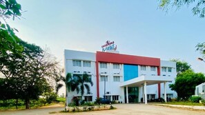 Un hôtel au design moderne, caractérisé par une palette de couleurs dominante en rouge et bleu, de nombreux étages et un espace d’entrée abrité.