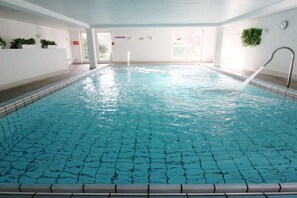 An indoor swimming pool with clear water, a diving board, and a wall-mounted plant. - Holiday Residence Albatros (Cuxhaven-Döse)