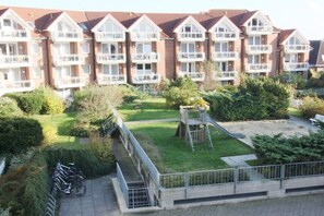 A residential building with multiple balconies, a grassy courtyard, and a playground. - Holiday Residence Albatros (Cuxhaven-Döse)
