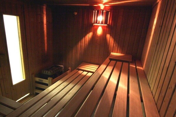 A sauna room with wooden benches and a bench on the left. - Holiday Residence Albatros (Cuxhaven-Döse)
