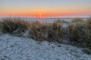 Ein Strand mit Dünen und einem Sonnenuntergang.