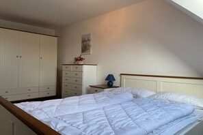 Een slaapkamer met een bed, een kaptafel, een nachtkastje en een wandlamp.