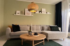 Ein Wohnzimmer mit einer Couch, einem runden Holztisch und einer Pendelleuchte.
