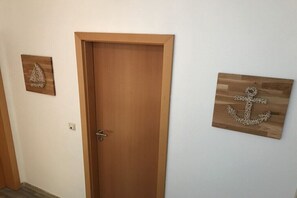 Ein Flur mit einer Holztür, einer Wanddekoration als Anker und einem dreieckigen Wandbild.