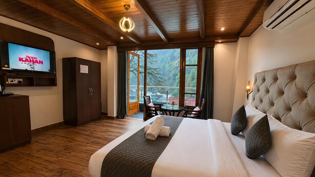 Habitación de hotel con cama, televisión, escritorio y vistas al exterior.