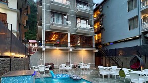 Una piscina con sillones de descanso y un edificio con balcones.
