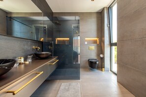 A modern bathroom with a large mirror, dark tiles, a black sink, and a glass-enclosed shower. - Villa Marro Zadarvillas (Privlaka)