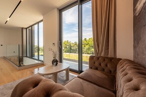 Ein modernes Wohnzimmer mit einem großen Schiebeglastür, einem runden Couchtisch und einer gemütlichen Couch.