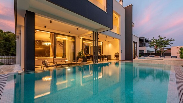 Ein modernes Haus mit Schwimmbad, großen Fenstern und Sitzgelegenheiten im Freien.