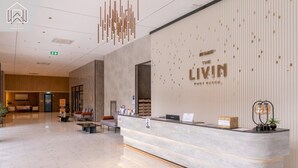 Et hotelreceptionsområde med en marmorindskrivning, en væg med hotellets navn og en moderne lysekrone.