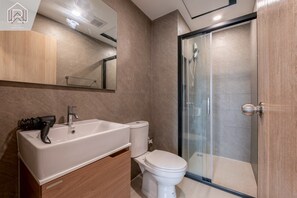 Uma casa de banho moderna com lavatório, sanita e cabine de duche envidraçada.