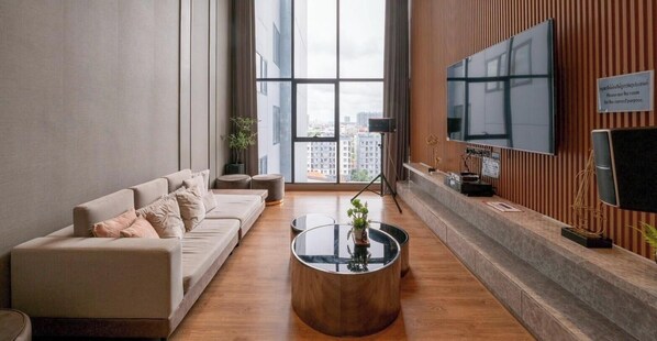 A modern living room with a sofa, a coffee table, a TV, and a view of the city.