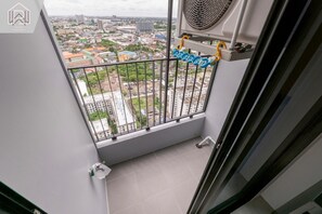 Uma varanda com vista para a cidade, uma janela com cortina e um ventilador.