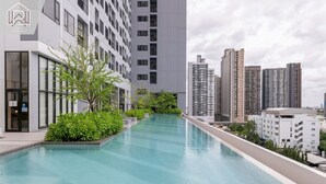 Ein modernes Gebäude mit Schwimmbecken, umgeben von Grünflächen und hohen Wohngebäuden.