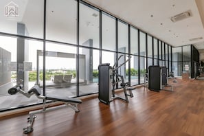 A modern gym with large windows, exercise equipment, and a view of the city. - Уютная современная квартира возле метро и ТЦ Аренда от 10 дней (Krung Thep Maha Nakhon)