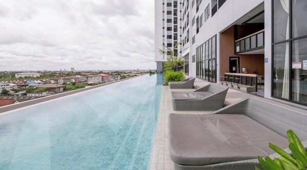 A rooftop infinity pool with a view of the city, a bar area with seating, and a modern building facade. - Уютная современная квартира возле метро и ТЦ Аренда от 10 дней (Krung Thep Maha Nakhon)