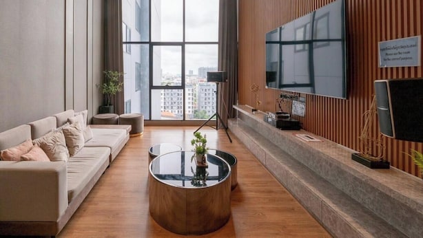 Un soggiorno moderno con un divano, un tavolino e una TV a schermo piatto montata a parete.