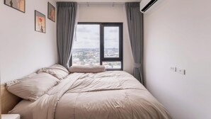 Una camera da letto con un letto, una finestra con tende, un condizionatore e vista sulla città.